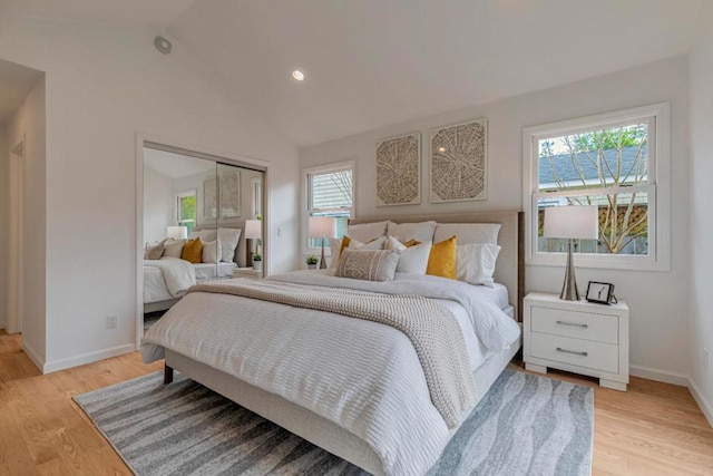 bedroom with multiple windows, vaulted ceiling, light hardwood / wood-style floors, and a closet