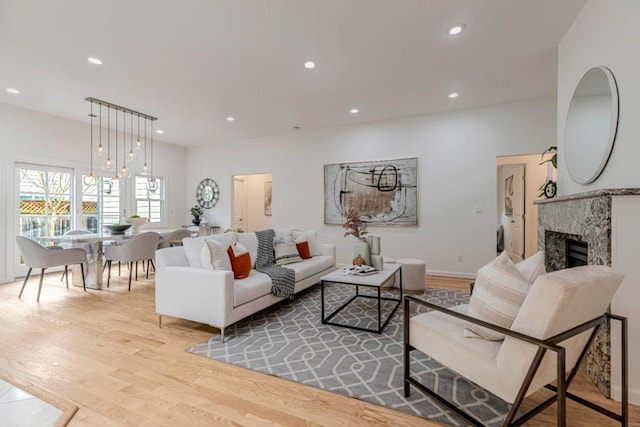 living room with a notable chandelier, a fireplace, and light wood-type flooring