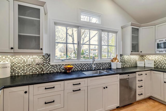 kitchen featuring sink, vaulted ceiling, light hardwood / wood-style flooring, appliances with stainless steel finishes, and white cabinets