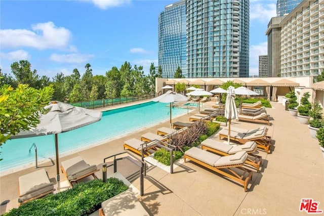 view of swimming pool featuring a view of the beach and a patio area