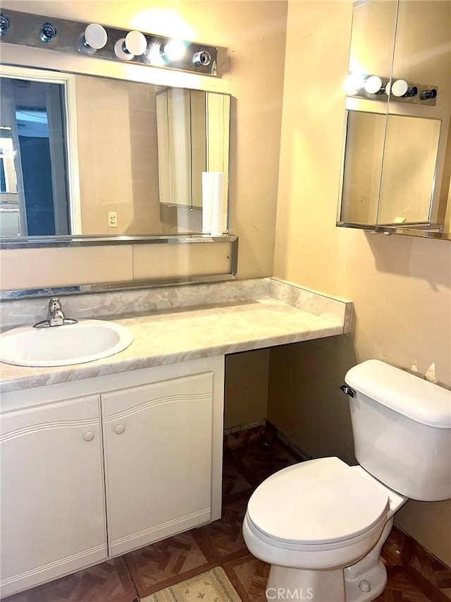 bathroom with vanity, parquet floors, and toilet