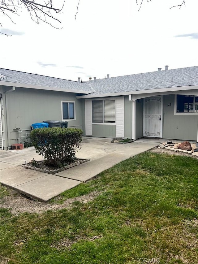 rear view of property with a yard and roof with shingles