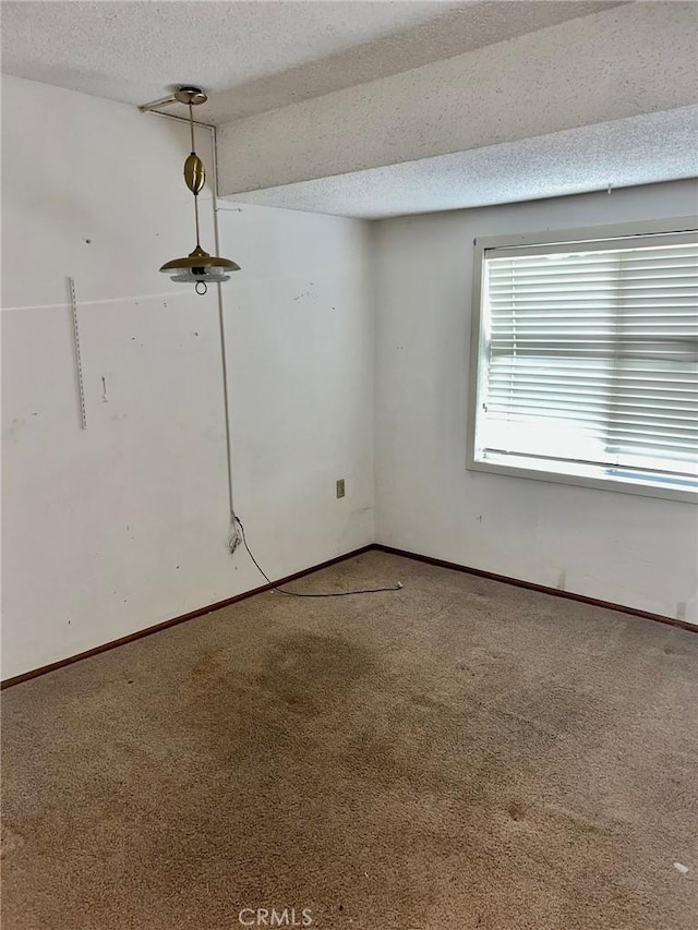carpeted empty room featuring baseboards and a textured ceiling