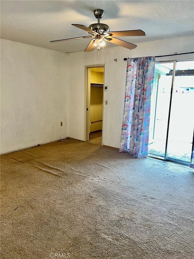 carpeted spare room featuring ceiling fan and a textured ceiling