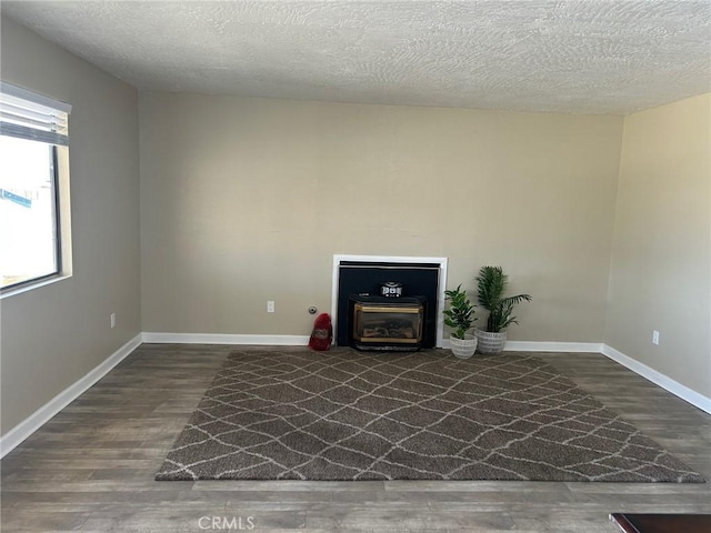 unfurnished living room featuring a textured ceiling, baseboards, and wood finished floors