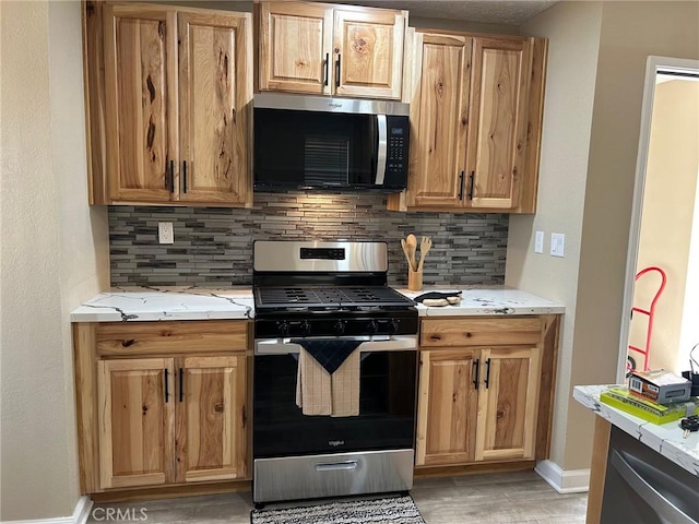 kitchen with appliances with stainless steel finishes, light hardwood / wood-style floors, and decorative backsplash