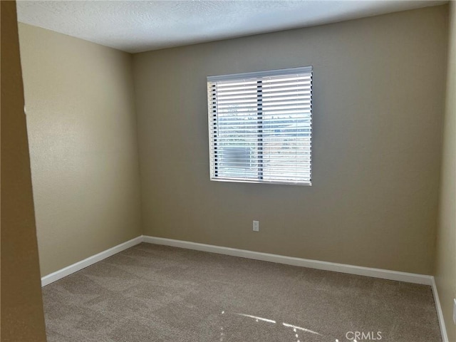 carpeted empty room featuring baseboards and a textured ceiling