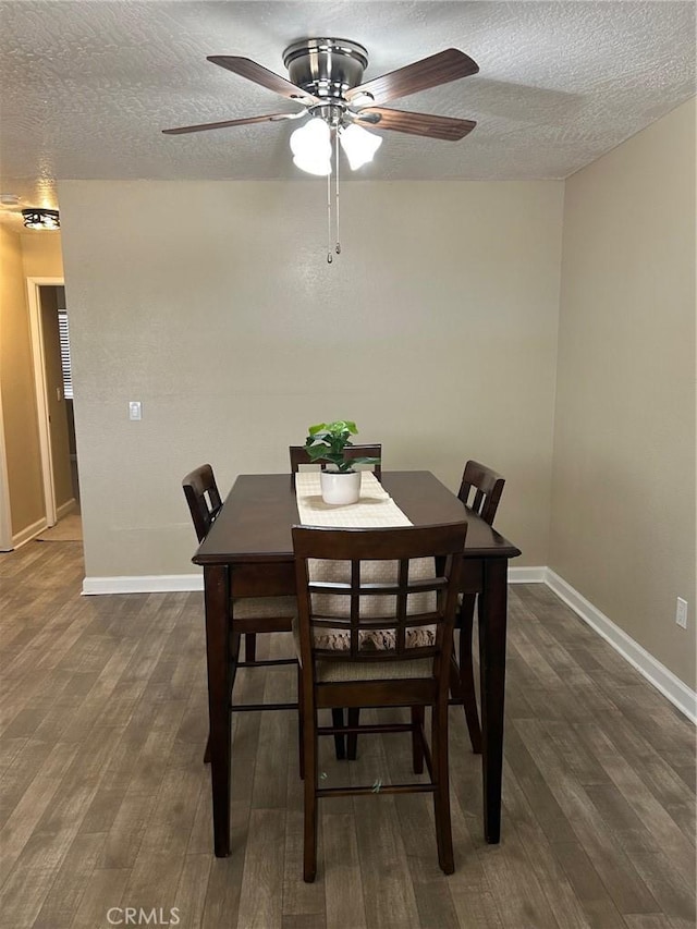 dining room featuring a textured ceiling, dark wood-type flooring, and baseboards