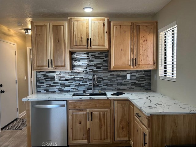 kitchen with decorative backsplash, dishwasher, a sink, and light stone countertops