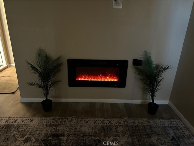 interior details featuring a lit fireplace, wood finished floors, and baseboards