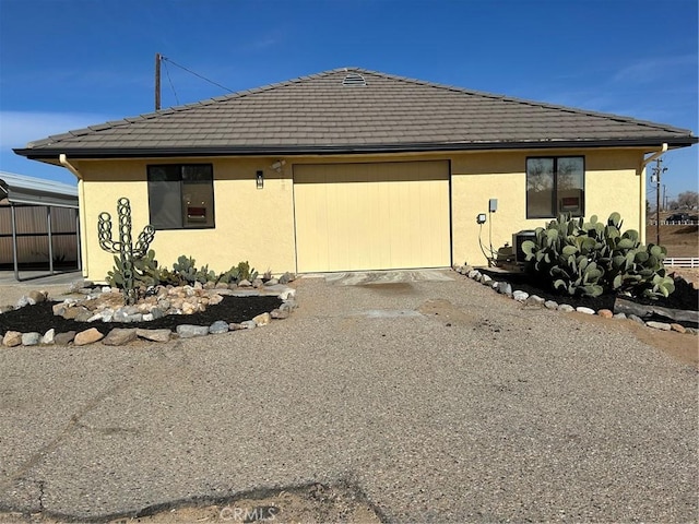 exterior space with driveway, an attached garage, a tile roof, and stucco siding