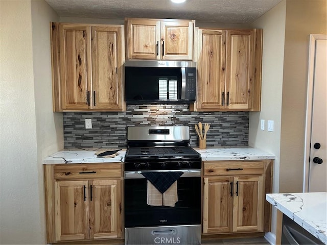 kitchen with light stone countertops, tasteful backsplash, appliances with stainless steel finishes, and a textured ceiling