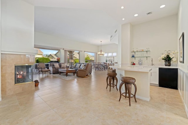 kitchen featuring a breakfast bar, a fireplace, white cabinetry, hanging light fixtures, and an inviting chandelier