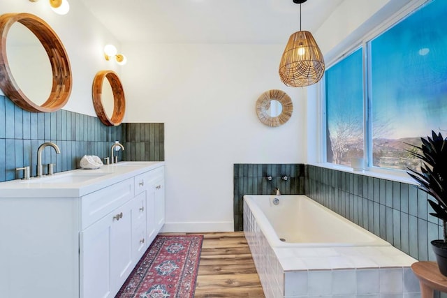 bathroom featuring vanity, hardwood / wood-style floors, and tiled bath