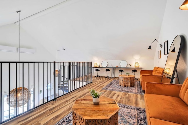 living area with hardwood / wood-style floors, lofted ceiling with beams, and an AC wall unit