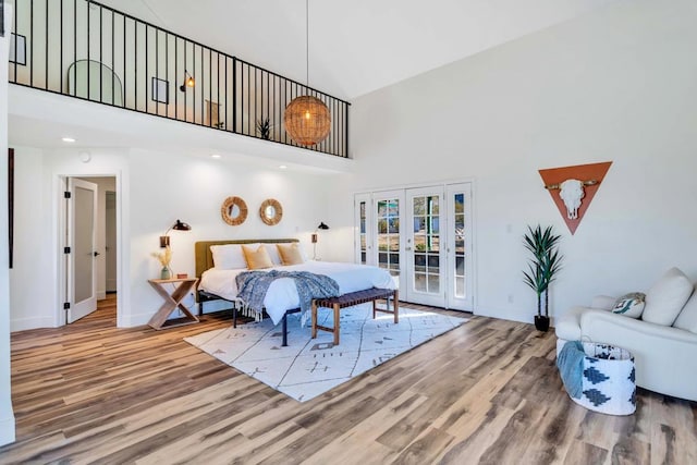 bedroom with hardwood / wood-style flooring, a towering ceiling, access to exterior, and french doors