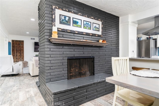 living room featuring a fireplace, light hardwood / wood-style floors, and a textured ceiling