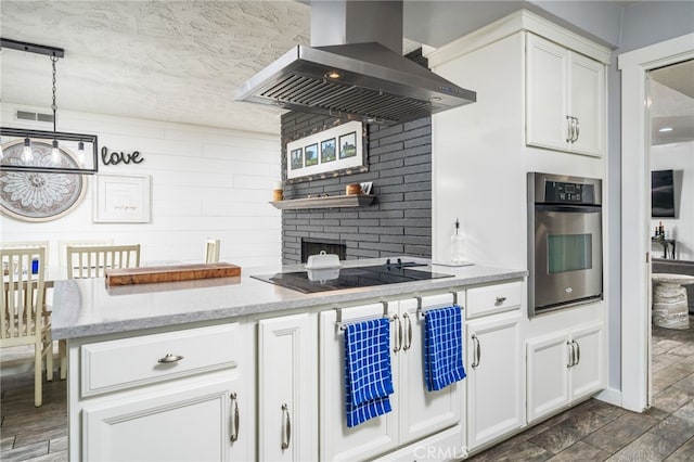 kitchen with decorative light fixtures, oven, black electric stovetop, range hood, and white cabinets