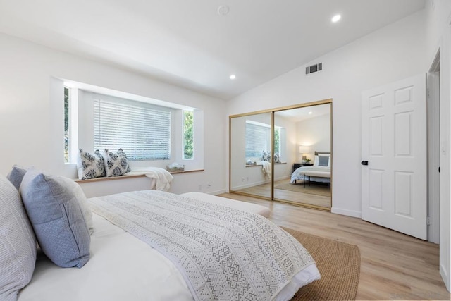 bedroom featuring vaulted ceiling, light hardwood / wood-style floors, and a closet