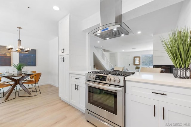 kitchen featuring gas range, island range hood, white cabinets, and light hardwood / wood-style floors