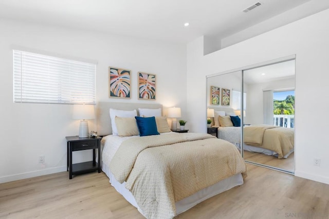 bedroom with a closet, vaulted ceiling, and light hardwood / wood-style flooring