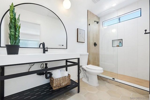 bathroom featuring tile patterned flooring, toilet, plenty of natural light, and a shower with shower door