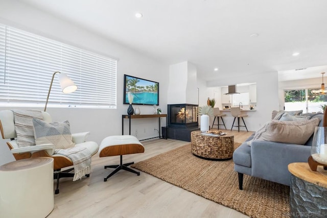 living room with light hardwood / wood-style flooring and a multi sided fireplace