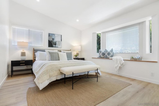 bedroom with lofted ceiling, multiple windows, and light hardwood / wood-style flooring