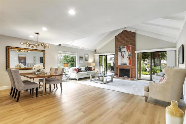 living room featuring high vaulted ceiling, a fireplace, light hardwood / wood-style floors, and a chandelier