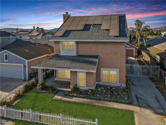 view of front facade with a garage, a yard, and solar panels