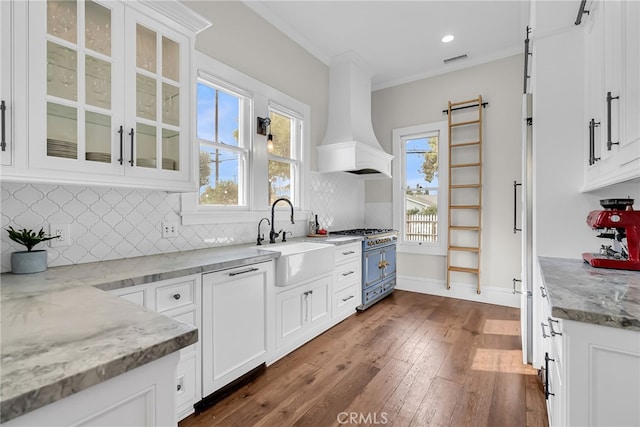 kitchen with white cabinetry, sink, custom range hood, and range with two ovens