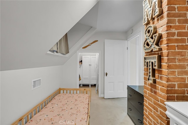 bedroom with lofted ceiling, light colored carpet, and brick wall