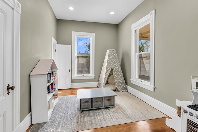 playroom with a healthy amount of sunlight and light hardwood / wood-style flooring