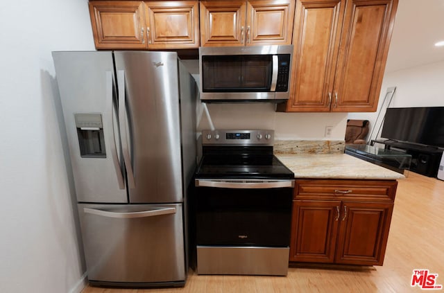 kitchen featuring light stone counters, stainless steel appliances, and light hardwood / wood-style flooring