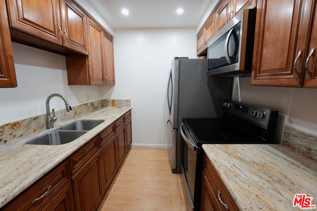 kitchen featuring light stone counters, sink, black range with electric cooktop, and light hardwood / wood-style flooring