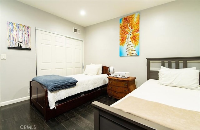 bedroom with dark hardwood / wood-style floors and a closet