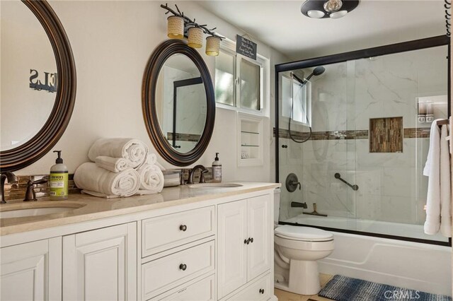 full bathroom featuring vanity, shower / bath combination with glass door, and toilet