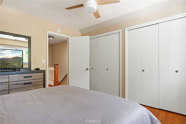 bedroom featuring ceiling fan, light hardwood / wood-style floors, and two closets