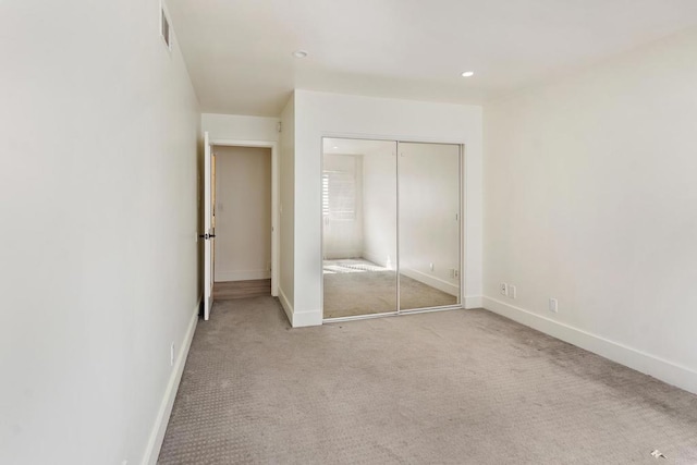 unfurnished bedroom featuring light colored carpet and a closet