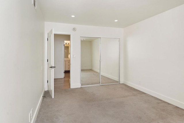 unfurnished bedroom featuring light colored carpet and a closet