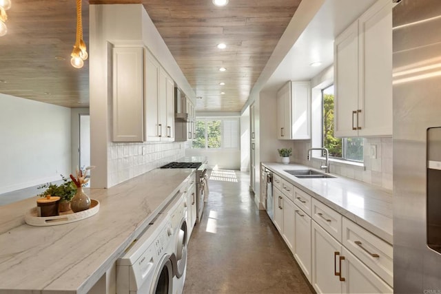 kitchen with sink, light stone counters, white cabinets, and independent washer and dryer