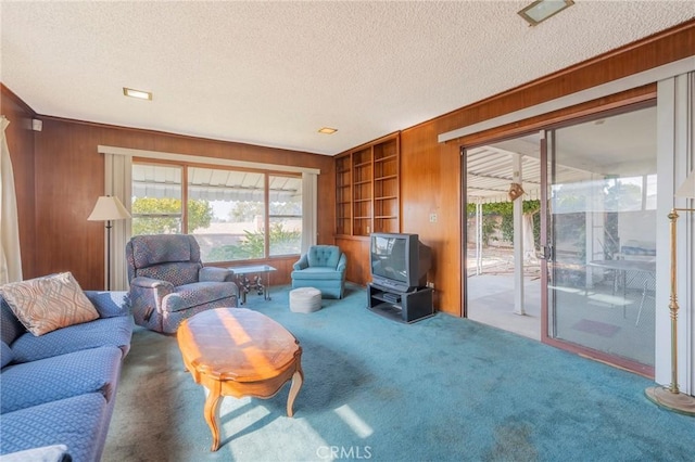 living room featuring carpet flooring, wooden walls, a textured ceiling, and built in features