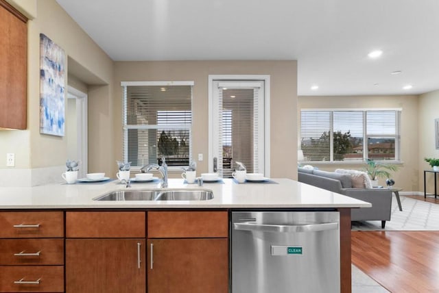 kitchen featuring stainless steel dishwasher, light hardwood / wood-style floors, sink, and kitchen peninsula