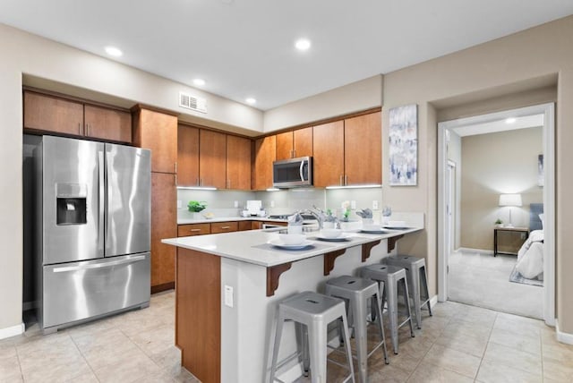 kitchen with light tile patterned flooring, a breakfast bar, appliances with stainless steel finishes, and kitchen peninsula