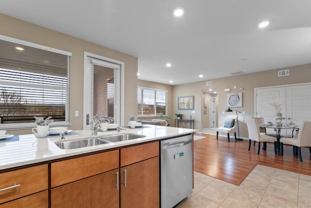 kitchen featuring dishwasher, sink, light stone countertops, and light tile patterned floors