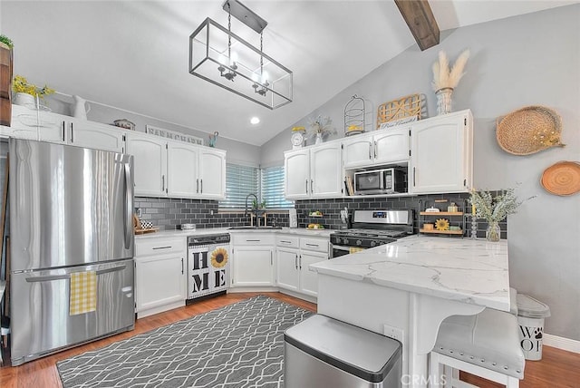 kitchen featuring sink, vaulted ceiling with beams, white cabinetry, kitchen peninsula, and stainless steel appliances