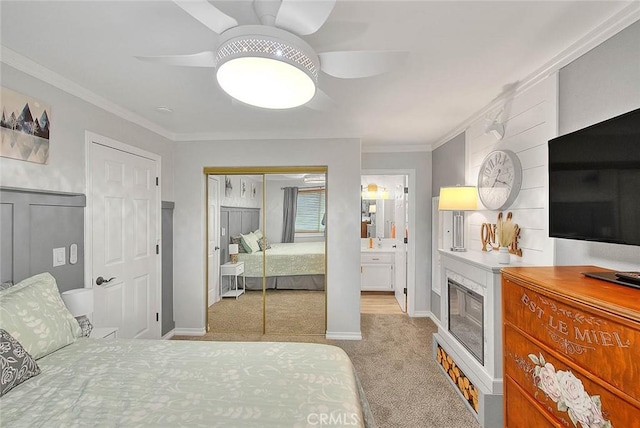 carpeted bedroom featuring connected bathroom, ornamental molding, a closet, and ceiling fan