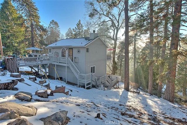 snow covered house with a wooden deck