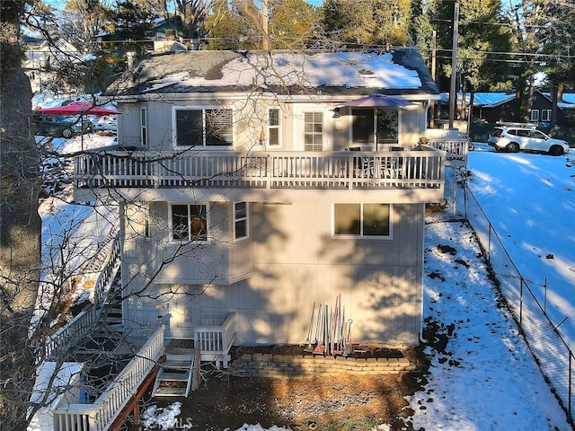 snow covered back of property featuring a balcony