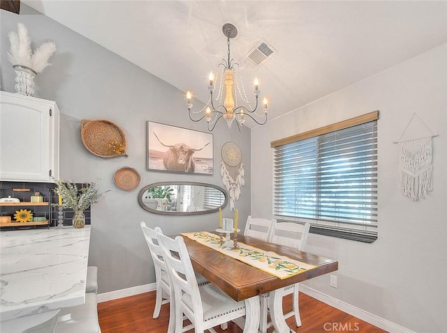 dining room featuring lofted ceiling, a notable chandelier, and wood-type flooring